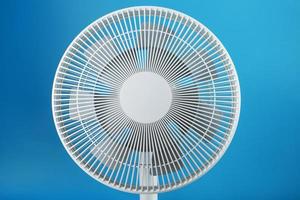 White modern electric fan for cooling the room on a blue background. photo