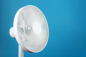 White modern electric fan for cooling the room on a blue background. photo
