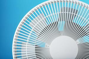 The grille and blades of the electric fan are white on a blue background photo