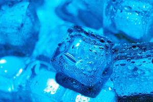 Ice cubes with water drops scattered on a blue background, top view. photo