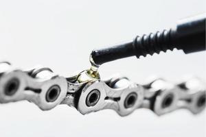 Lubricating a bicycle chain with a drop of oil close-up on an isolated gray background photo