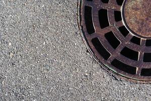 Sewer round hatch with a grate on an asphalt road. photo