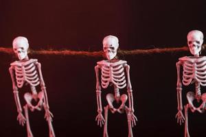 Skeletons hang on a rope on a black background with red illumination photo