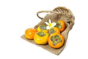 Persimmon with sack and wicker basket isolated on white background photo