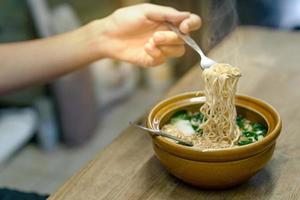 Hand holding a fork with instant noodles photo