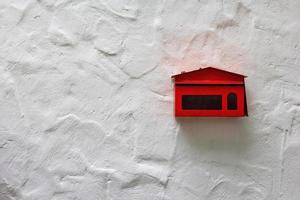 red mailbox on white concrete wall photo