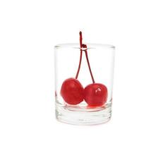 Maraschino cherry in glass cup isolated on white background photo