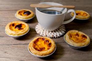 coffee with egg tart in aluminum foil cup on wood table photo