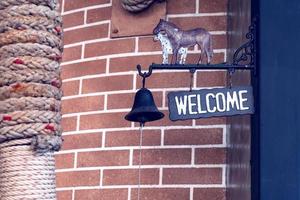 welcome sign with black bell on pole photo