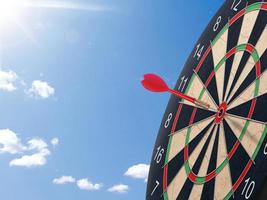 Darts with dartboard with blue sky background concept for hitting target, goal and success photo