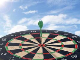 Darts with dartboard with blue sky background concept for hitting target, goal and success photo