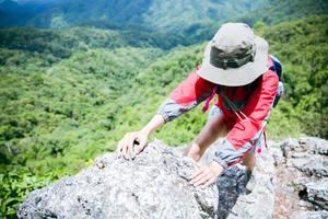 Young person hiking female climbing on top rock, Backpack woman looking at beautiful mountain valley at sunlight in summer, Landscape with sport girl, high hills, forest, sky. Travel and tourism. photo