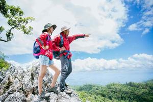 Young tourist couple watching spectacular mountain scenery in high mountains. man and woman hiker on top rock. A couple of travelers in love. People greet the dawn. Lovers travel. Copy space photo