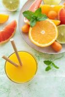 vaso de jugo y frutas cítricas foto