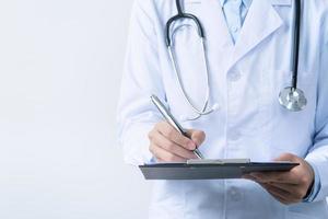 Doctor with stethoscope in white coat holding clipboard, writing medical record diagnosis, isolated on white background, close up, cropped view. photo