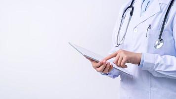 Doctor with stethoscope in white coat holding tablet, showing medical information, diagnosis, isolated on white background, close up, cropped view. photo