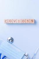 COVID-19 word wooden cube with mask, medical equipment, world disease pandemic infection and prevention concept, top view, flat lay, overhead design photo