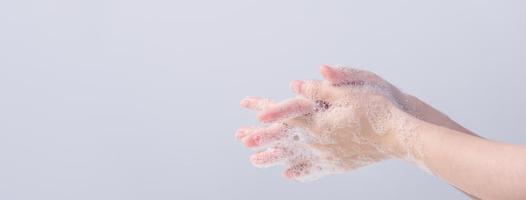 Washing hands. Asian young woman using liquid soap to wash hands, concept of hygiene to protective pandemic coronavirus isolated on gray white background, close up. photo