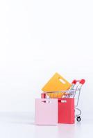 Shopping bags in a silver red shopping cart isolated on white table background, concept of staying home order, close up, copy space design. photo