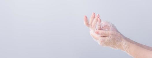 Washing hands. Asian young woman using liquid soap to wash hands, concept of hygiene to protective pandemic coronavirus isolated on gray white background, close up. photo