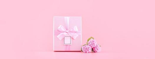 concepto de diseño de regalo de vacaciones del día de la madre, ramo de flores de clavel rosa con caja envuelta, carrito de compras, bolsa, aislado en fondo rosa claro, espacio de copia. foto