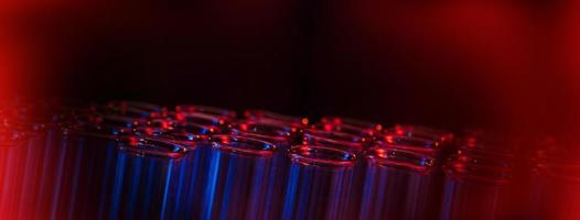 Test tube row. Concept of medical or science laboratory, liquid drop droplet with dropper in blue red tone background, close up, micro photography picture. photo