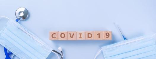 covid-19 palabra cubo de madera con máscara, equipo médico, concepto de prevención e infección pandémica de enfermedades mundiales, vista superior, plano, diseño superior foto