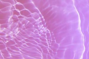 Defocus blurred transparent purple colored clear calm water surface texture with splash, bubble. Shining purple water ripple background. Surface of water in swimming pool. Tropical purple water color. photo