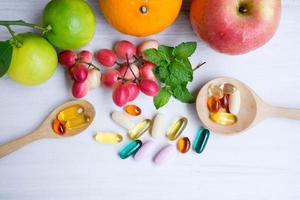 Multivitamin supplements from fruit on white wooden background photo