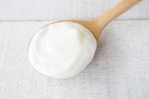 White yogurt on wooden spoon on white wood background. photo