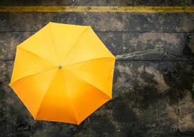 un paraguas naranja en un día lluvioso sobre fondo de hormigón húmedo .vista superior foto