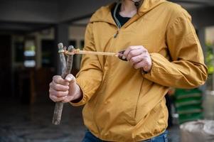 Someone using a wood slingshot for shooting somethings. and A slingshot works like a small catapult, with rubber strips holding a stone or other projectile sits. photo