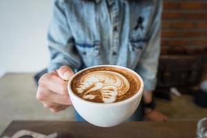 la taza de café con leche con el arte del café con leche en la superficie para el día escalofriante. foto