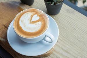 la taza de café con leche con el arte del café con leche en la superficie para el día escalofriante. foto