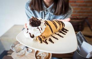 The sweet dessert chocolate banana crepes on her hand. photo