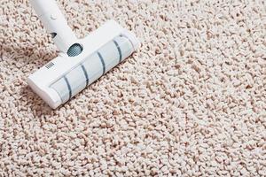 A white turbo brush of a cordless vacuum cleaner on the carpet. Indoor cleaning concept photo