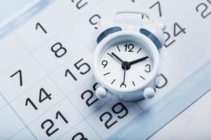 Alarm clock and calendar on a blue background photo