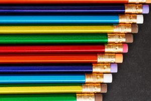 Colorful pencils with erasers in a row on a black background