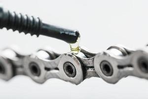 lubricando una cadena de bicicleta con una gota de aceite de cerca en un fondo gris aislado foto