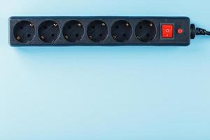 A black surge protector with portable sockets and a red button on a blue background. photo