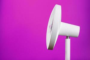 Electric fan in white with a modern design for cooling the room on a pink background. photo