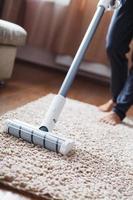 The turbo brush of a cordless vacuum cleaner cleans the carpet in the house in close-up photo