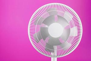 Electric fan in white with a modern design for cooling the room on a pink background. photo