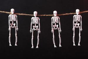 esqueletos decorativos cuelgan de una cuerda sobre un fondo sombrío foto