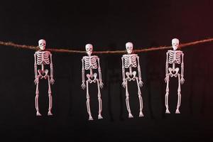 Four skeletons suspended by the neck on a rope with silhouettes on a dark background photo