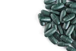 Green spirulina pills with multivitamins on a white background. photo