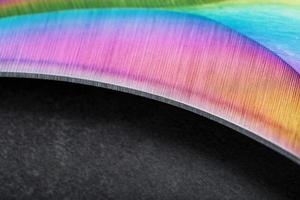 la hoja afilada del cuchillo kerambit de acero es multicolor en primer plano sobre un fondo oscuro. foto