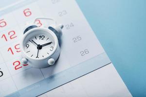 Alarm clock and calendar on a blue background photo