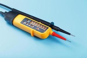 Yellow tester for step-by-step indication of voltage in an electrical circuit on a blue background. photo