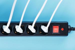 Electric mains filter with inserted white plugs of electrical appliances on a blue background. photo